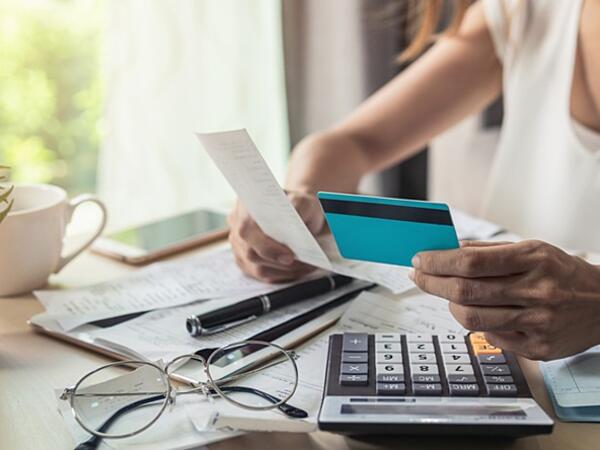person looking at credit card statement with calculator